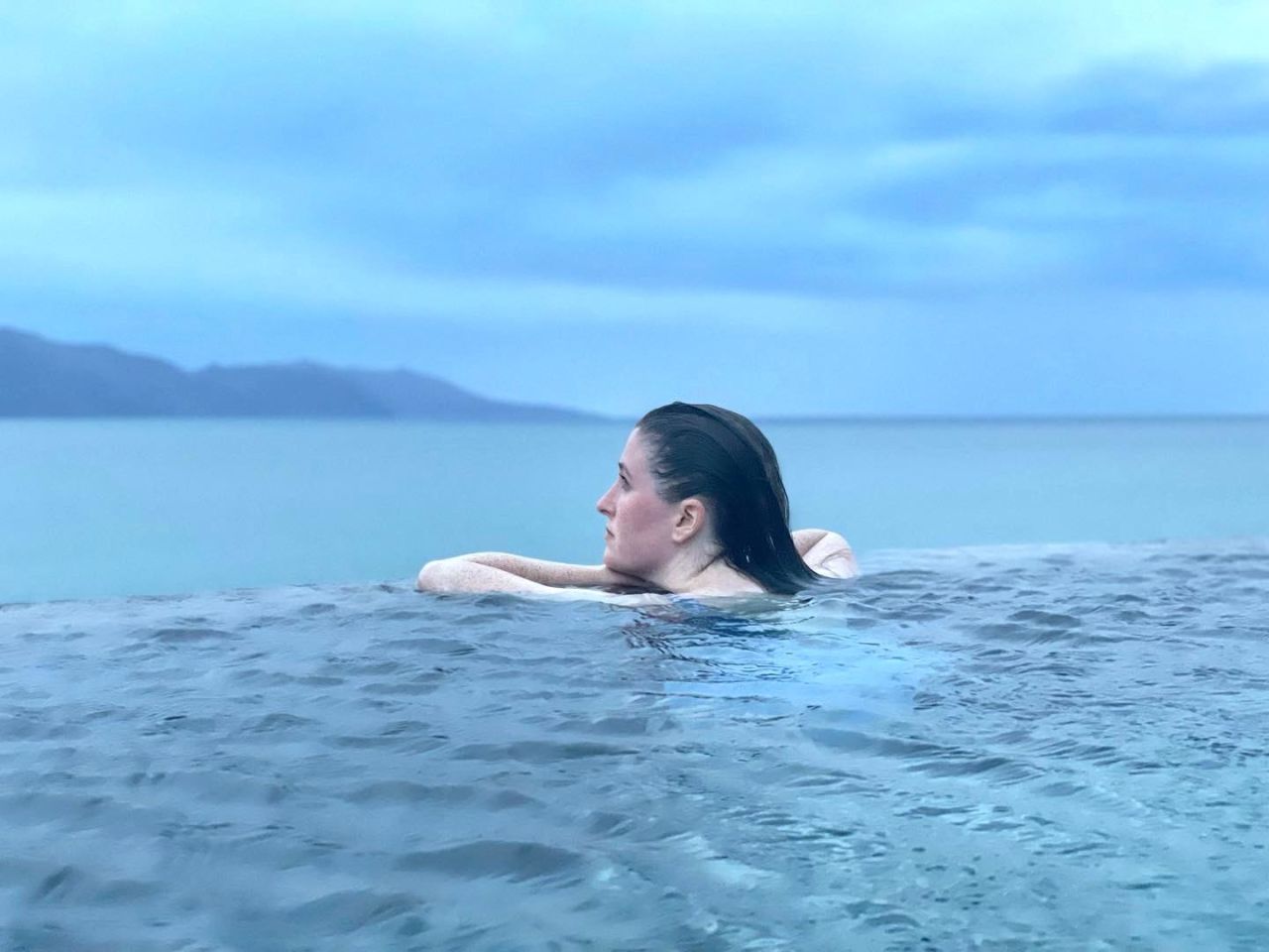 Woman in thermal pool overlooking ocean 